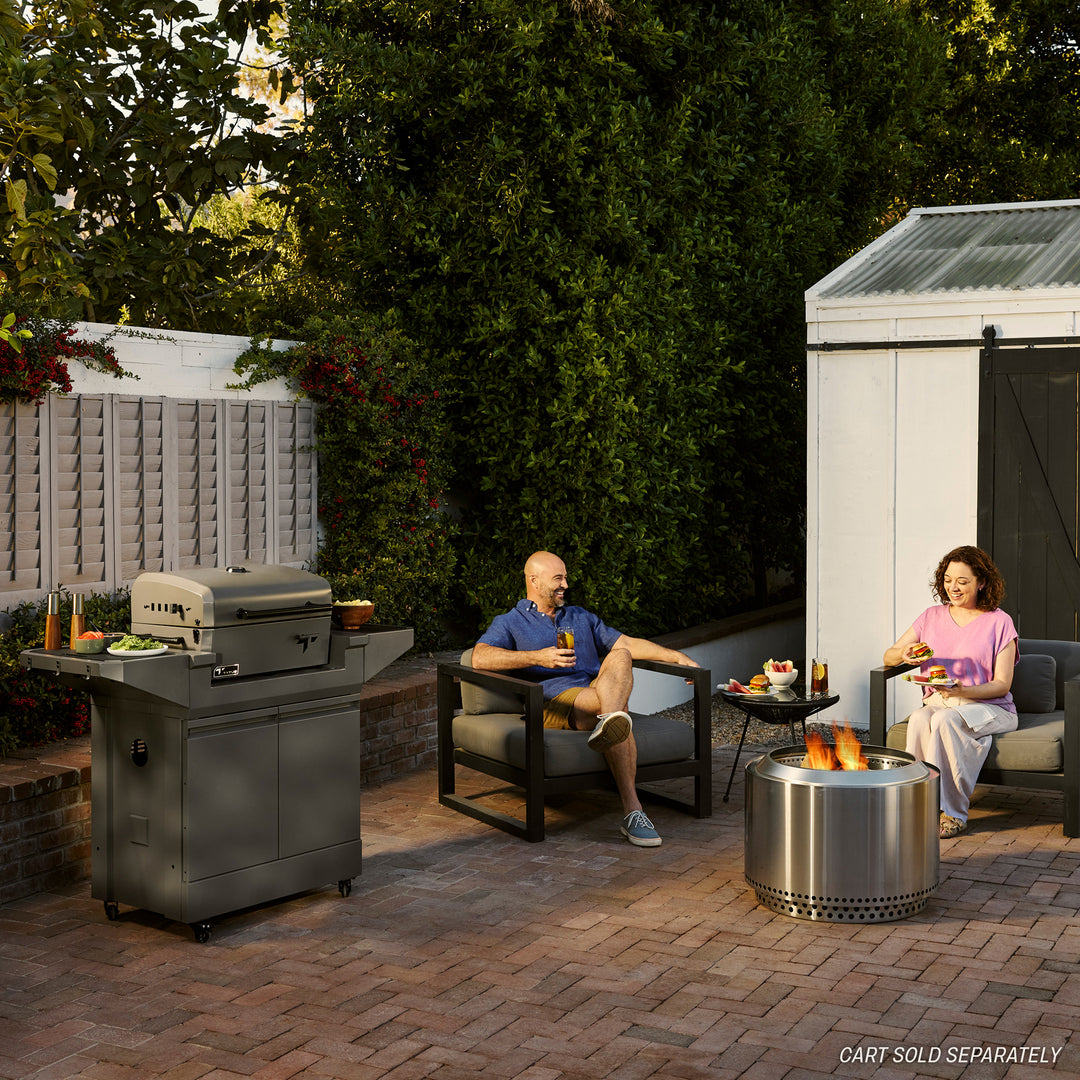 Couple enjoying patio grilling with a TYTUS stainless steel outdoor grill and fire pit, showcasing premium grilling solutions.