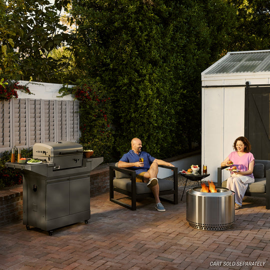 Couple enjoying patio grilling with a TYTUS stainless steel outdoor grill and fire pit, showcasing premium grilling solutions.