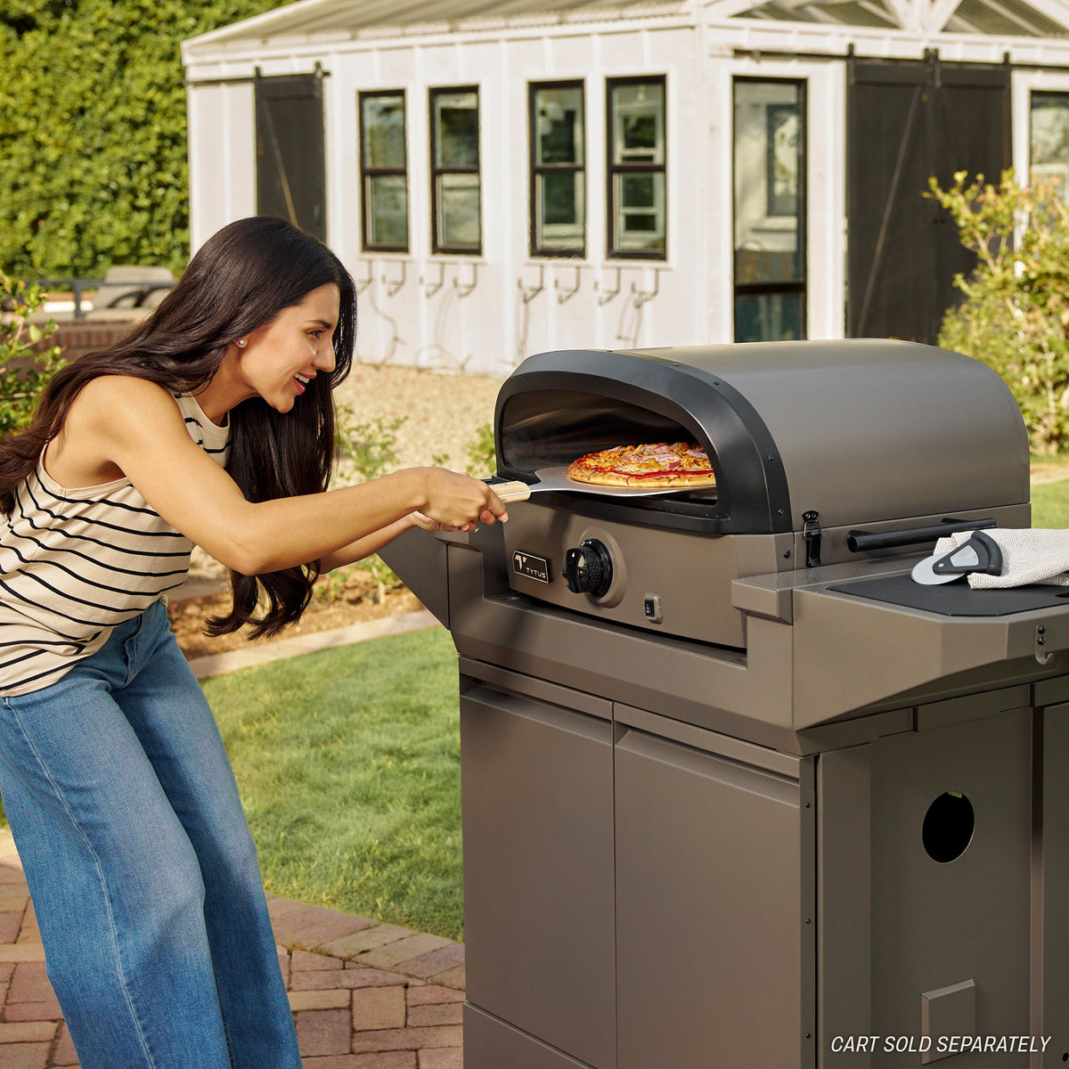 Woman using TYTUS stainless steel outdoor grill with pizza stone for patio grilling solutions.