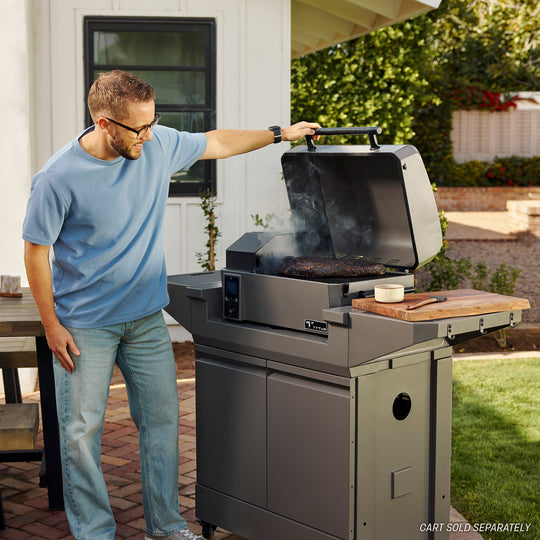 Man grilling on a TYTUS stainless steel outdoor grill with premium accessories.